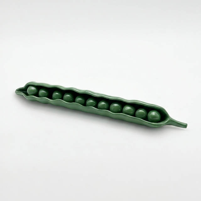 Green ceramic pea pod with peas on a white background
