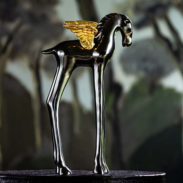 Decorative horse figurine with gold wings on a blurred natural background
