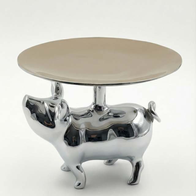 Round table with a metallic pig-shaped base on a white background
