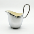 Silver creamer with a white interior on a white background